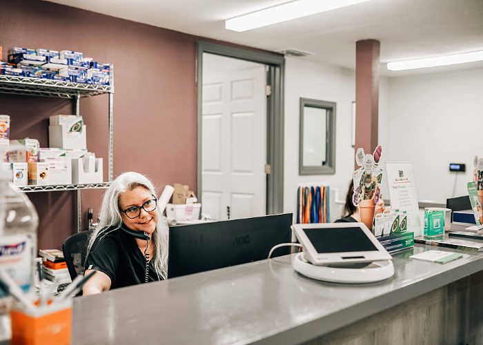 Woman sitting on phone at computer at reception area desk